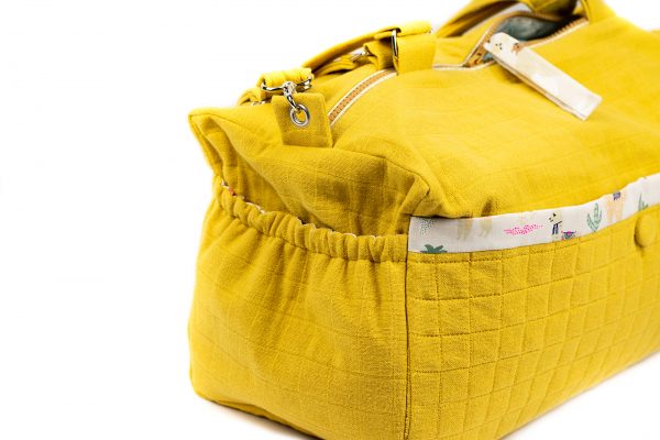 Gros plan sur la poche de côté du sac à langer jaune moutarde.